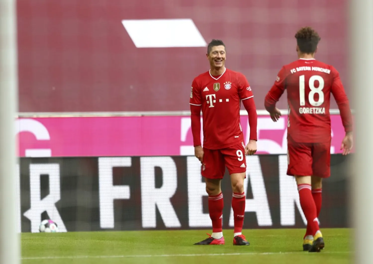 Bayern's Robert Lewandowski, left, celebrates with Leon Goretzka after scoring his side’s third goal during the Bundesliga match against VfB Stuttgart in Munich, Germany, March 20, 2021. (AP)