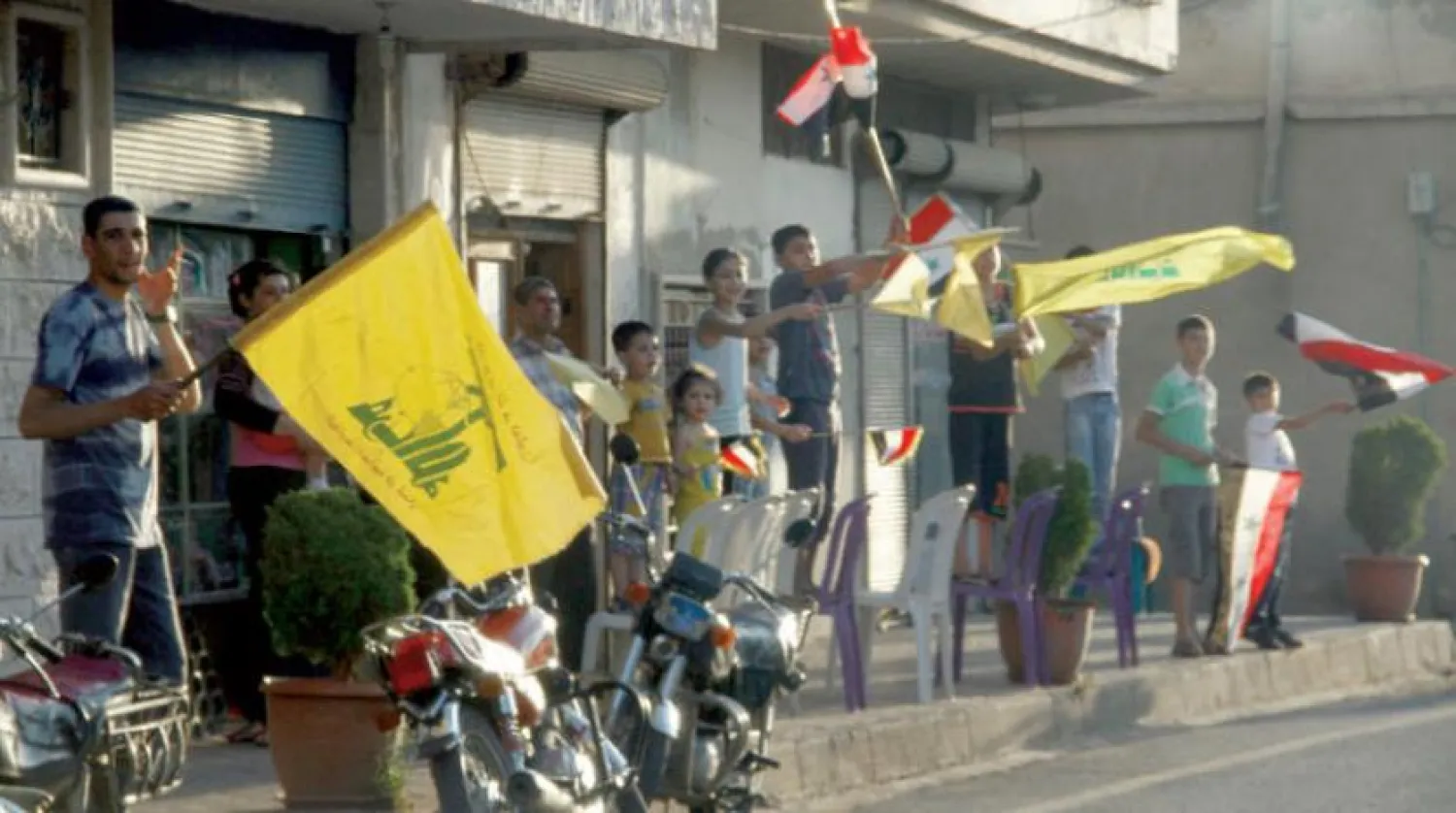 Kuseyr’deki Suriyeliler Haziran 2013’te Hizbullah ve Suriye bayrağı taşırken (AFP)