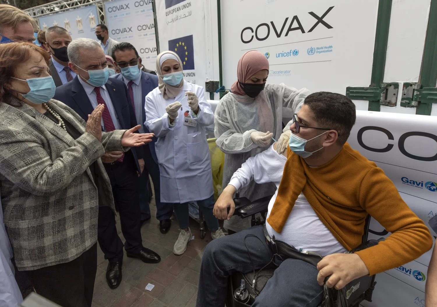 Health Minister Mai Alkaila, left, and Palestinian Prime Minister Mohammad Shtayyeh, second left watch as a man receives a shot of the Pfizer COVID-19 vaccine during a campaign to vaccinate front-line workers, those over 75, cancer patients and medical personnel, at the health ministry in the West Bank city of Ramallah, Sunday, March 21, 2021. (AP Photo/Nasser Nasser)