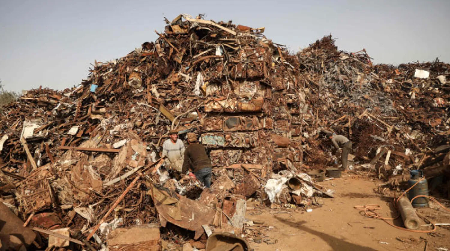 عمال فلسطينيون يبحثون في موقع لنفايات معدنية بغزة (إ.ف.ب)