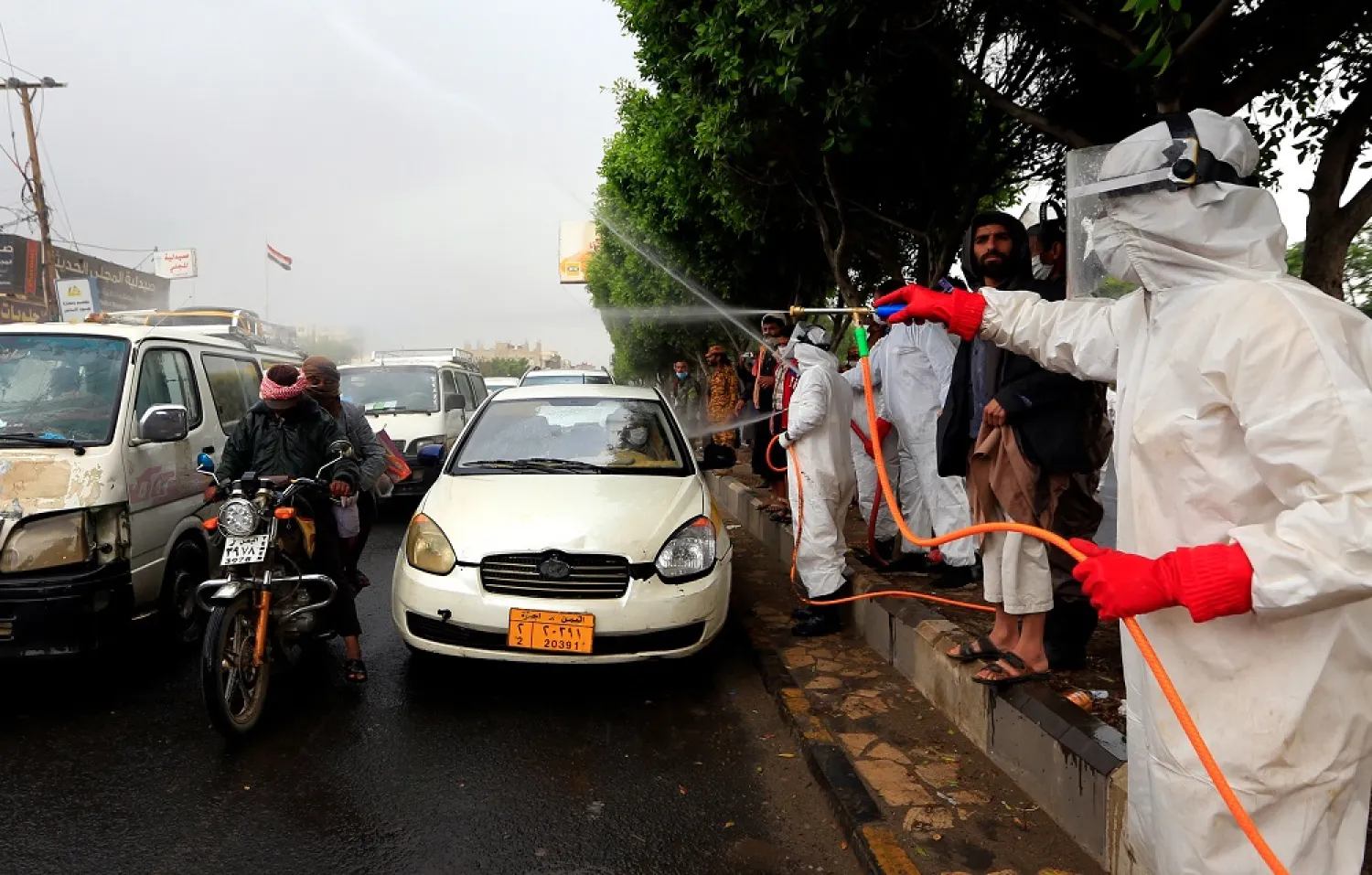 Yemeni workers wearing protective outfits spray disinfectant on passing cars and motorcycles in the capital Sanaa, during the ongoing novel coronavirus pandemic, on May 21, 2020. (Getty Images)