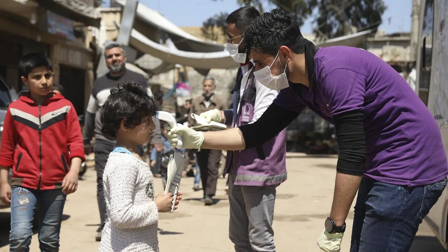 A member of a non-governmental aid organization measures temperature as a preventive measure for coronavirus in the town of Kafr Takharim, Idlib province, Syria, April 14, 2020. (AP)