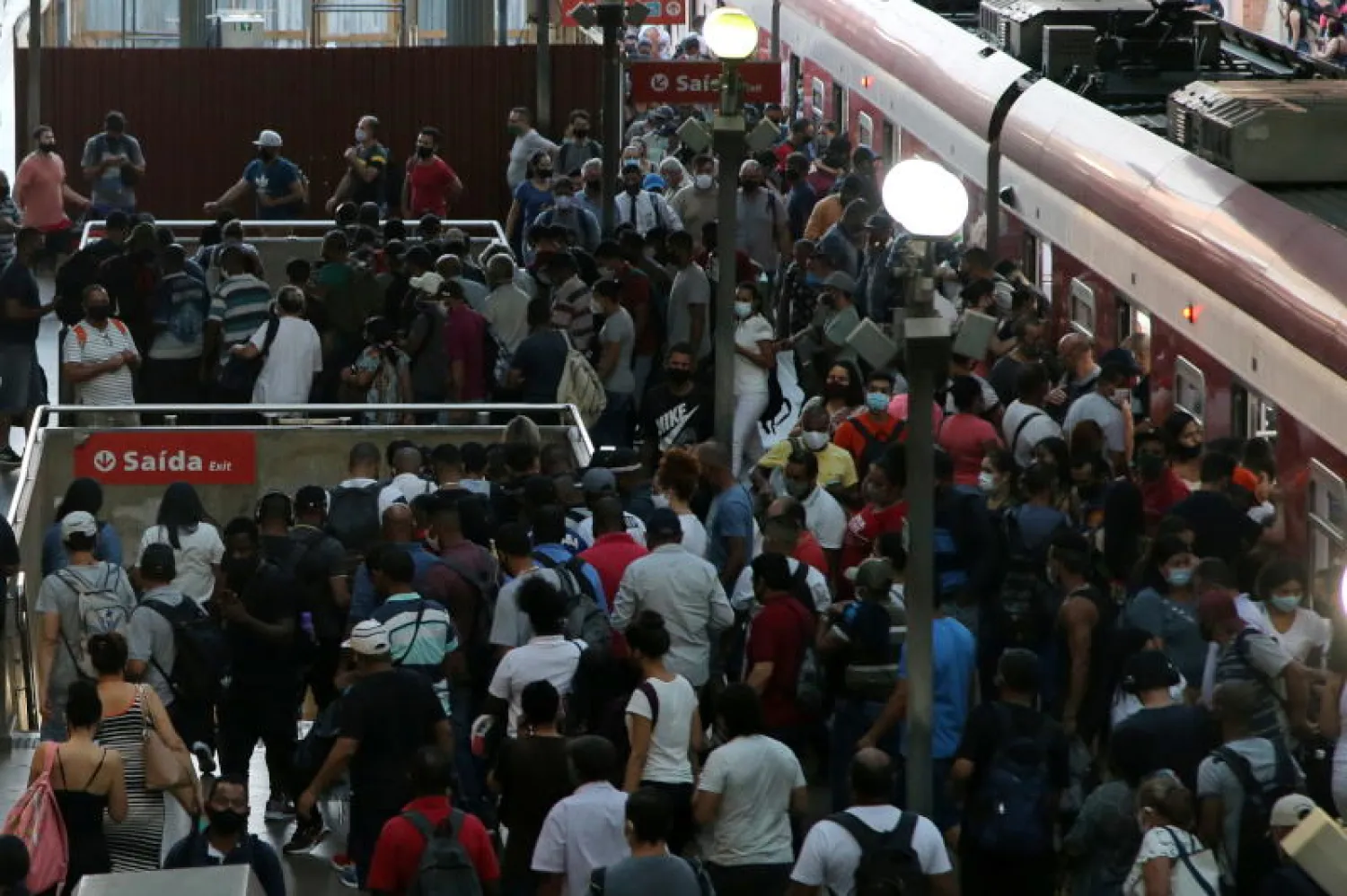 أشخاص يمشون بعد نزولهم من قطار بمحطة «لوز» في ساو باولو (رويترز)