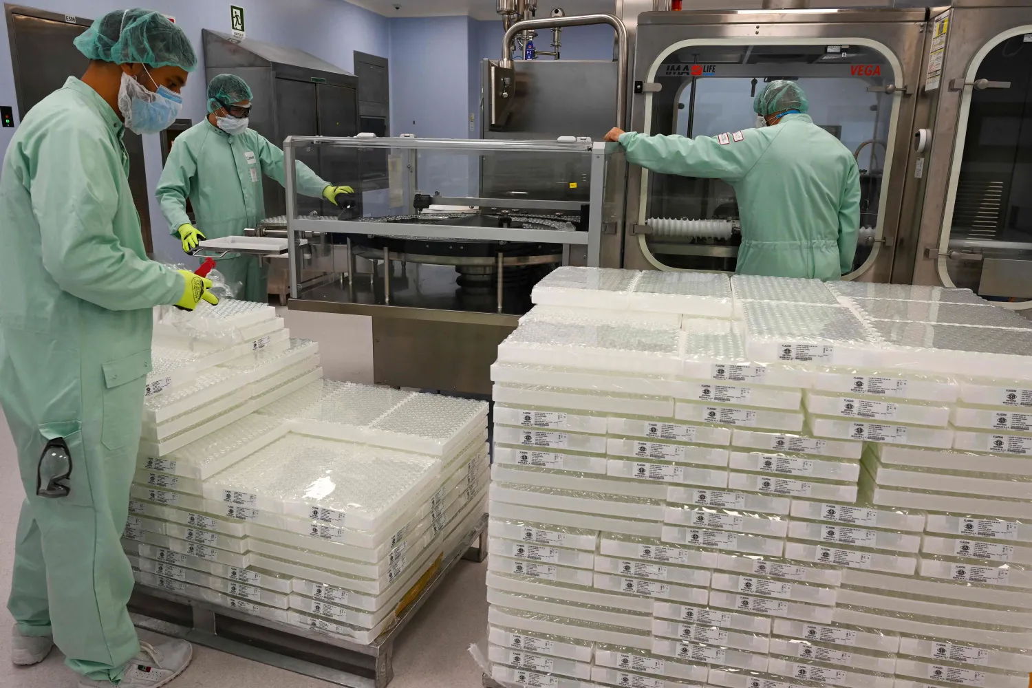 فنيون بمصنع «كاتالينت» يقمومن باختبارات التعبئة والتغليف كجزء من إنتاج كميات ضخمة من لقاح أسترازينيكا (ا.ف.ب)