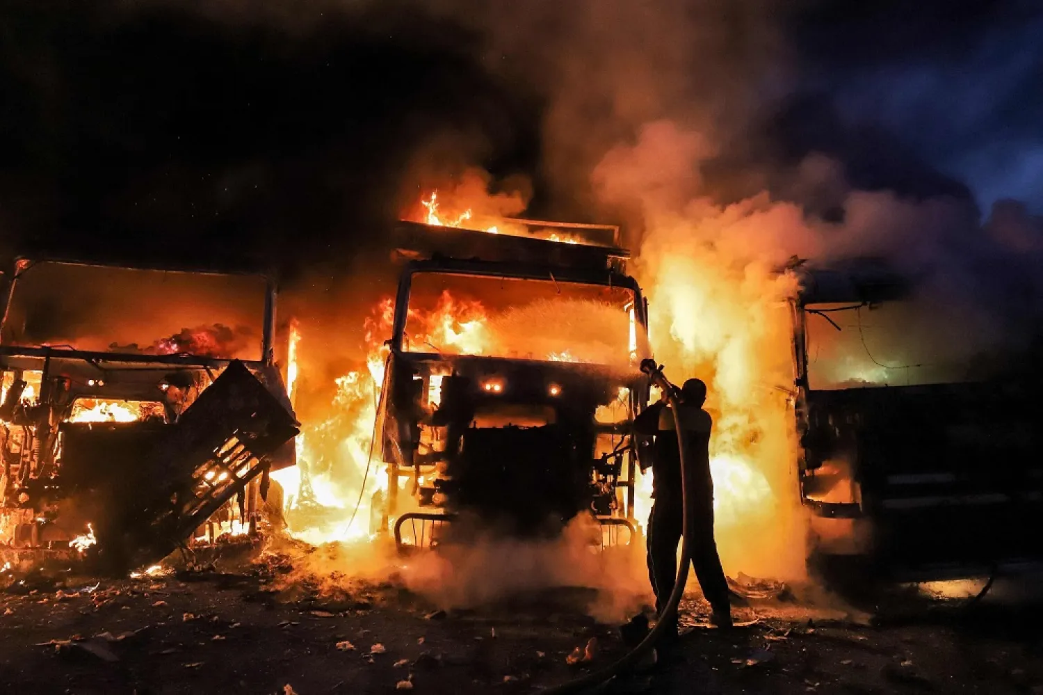 Syrian civil defense members try to put out several vehicles in the aftermath of airstrikes near the Bab al-Hawa border crossing between Syria and Turkey in the Idlib province, Syria, March 21, 2021. (AFP)