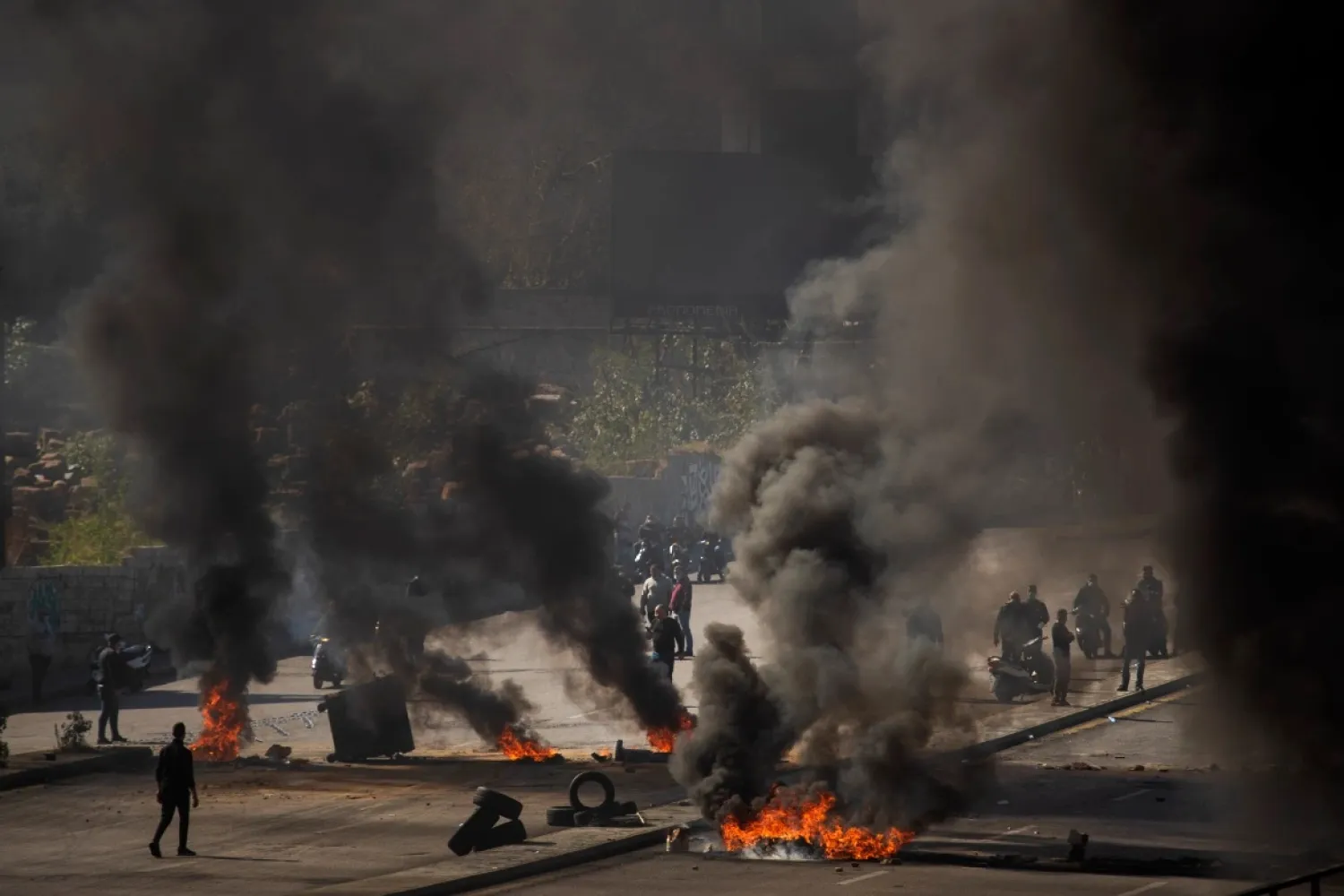 Protesters stand in front of burning tires that block a main road during protests in Beirut. (AP file photo)