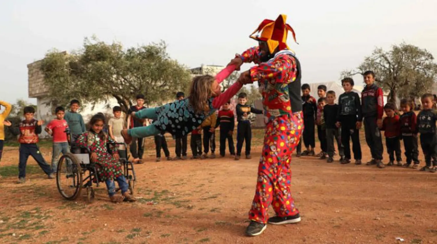 A Syrian comedian, who dresses up as a clown to entertain children in camps for displaced Syrians in the northwest of the country, performs in the main square of a camp in Kfar Jalis north of Idlib on March 22, 2021. (Photo by Zein Al RIFAI / AFP)