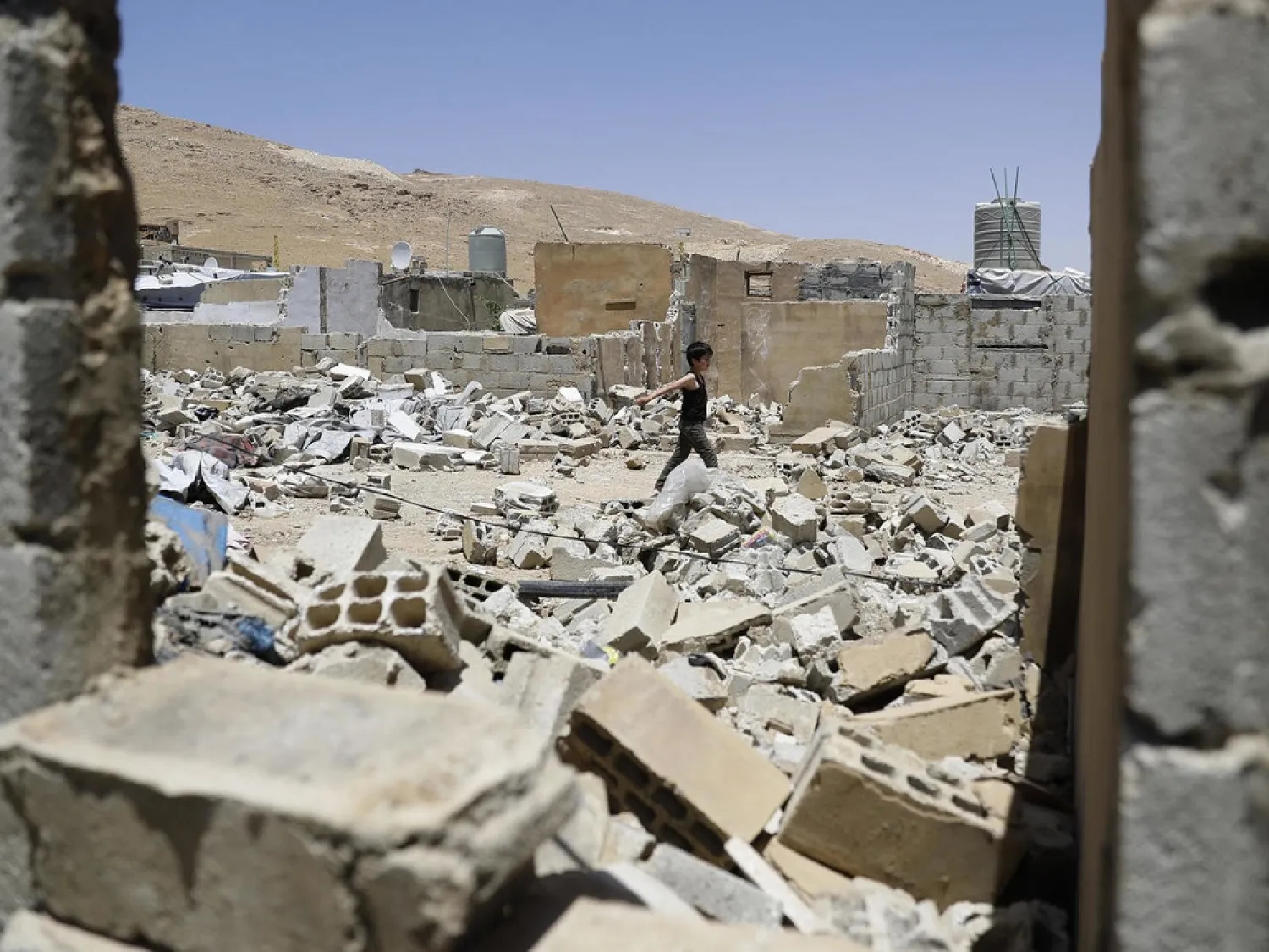 A Syrian boy walks among demolished shelters at a refugee camp in the northeastern Lebanese town of Arsal, in the Bekaa Valley. (AFP)
