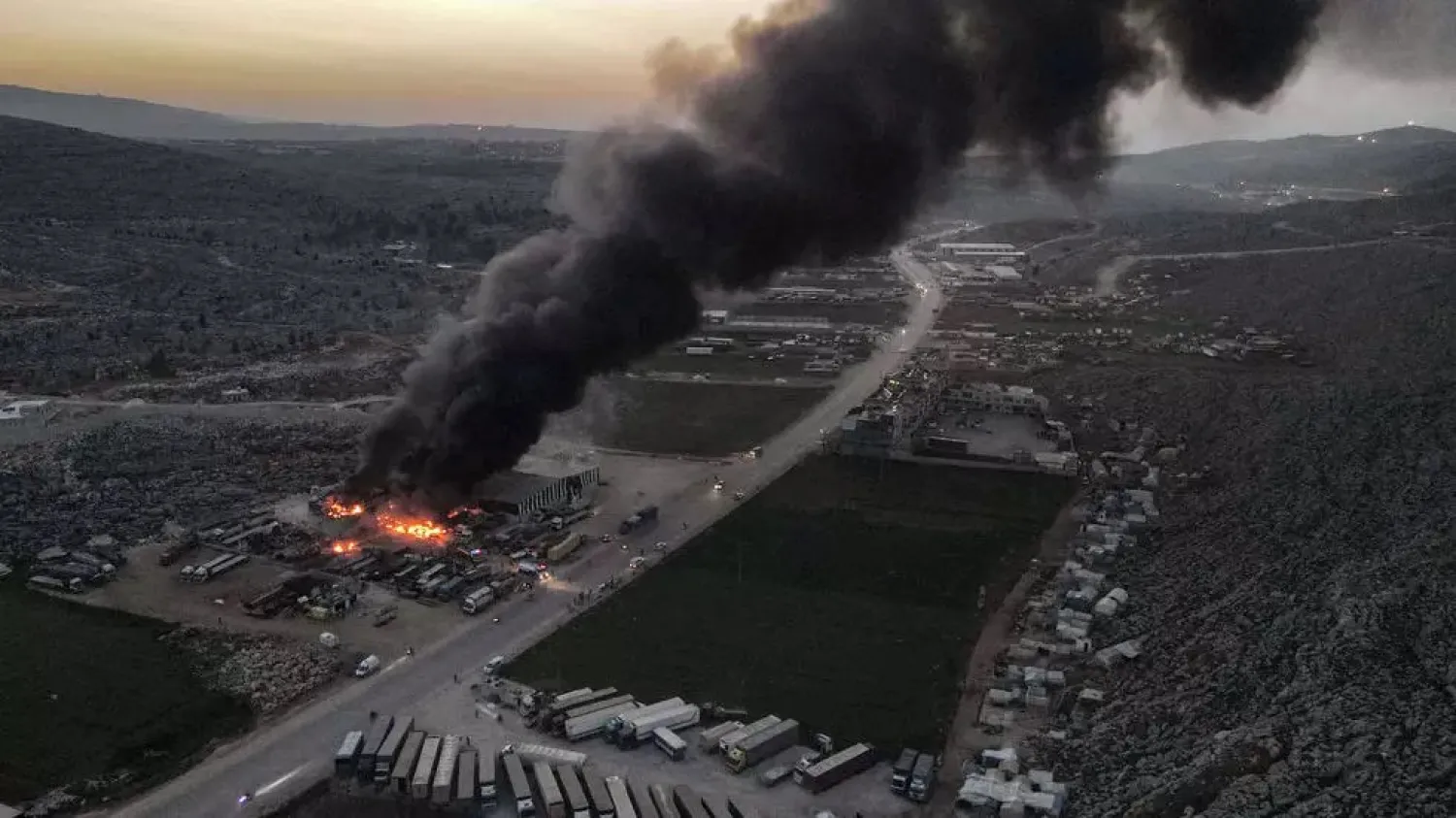 Smoke billows from burning trucks and freight vehicles on March 21, 2021 in the aftermath of air strikes at a depot near the Bab al-Hawa, the sole border crossing into Syria. (AFP)