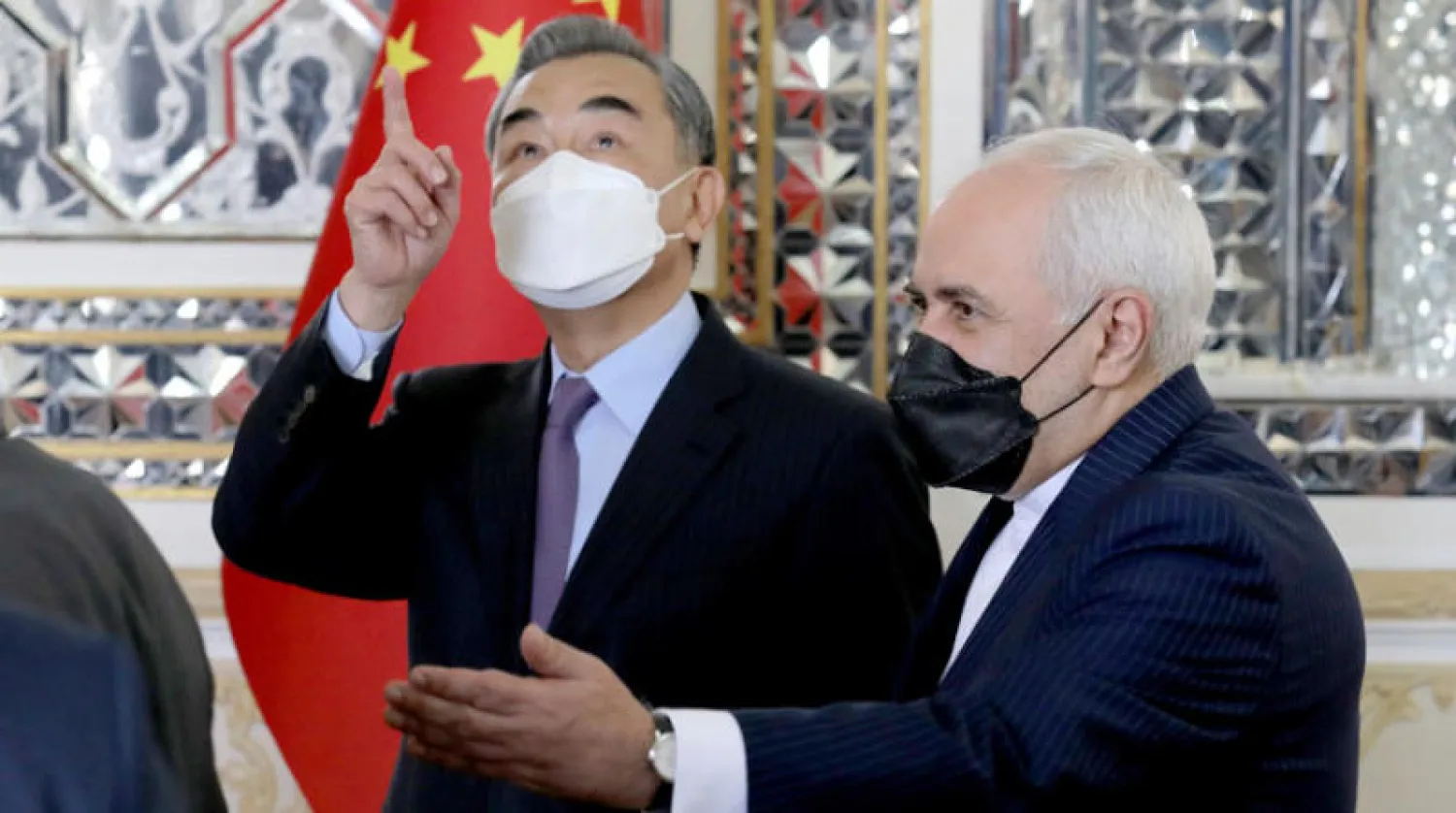 وزير الخارجية الصيني وانغ يي لدى استقباله من نظيره الإيراني محمد جواد ظريف في طهران السبت (أ.ب)