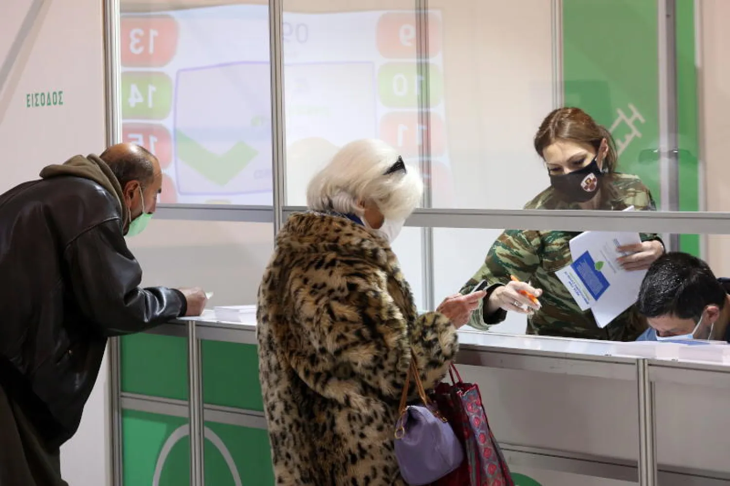 مسنّان يسجلان اسميهما بمركز عسكري في أثينا لتلقي اللقاح (إ.ب.أ)