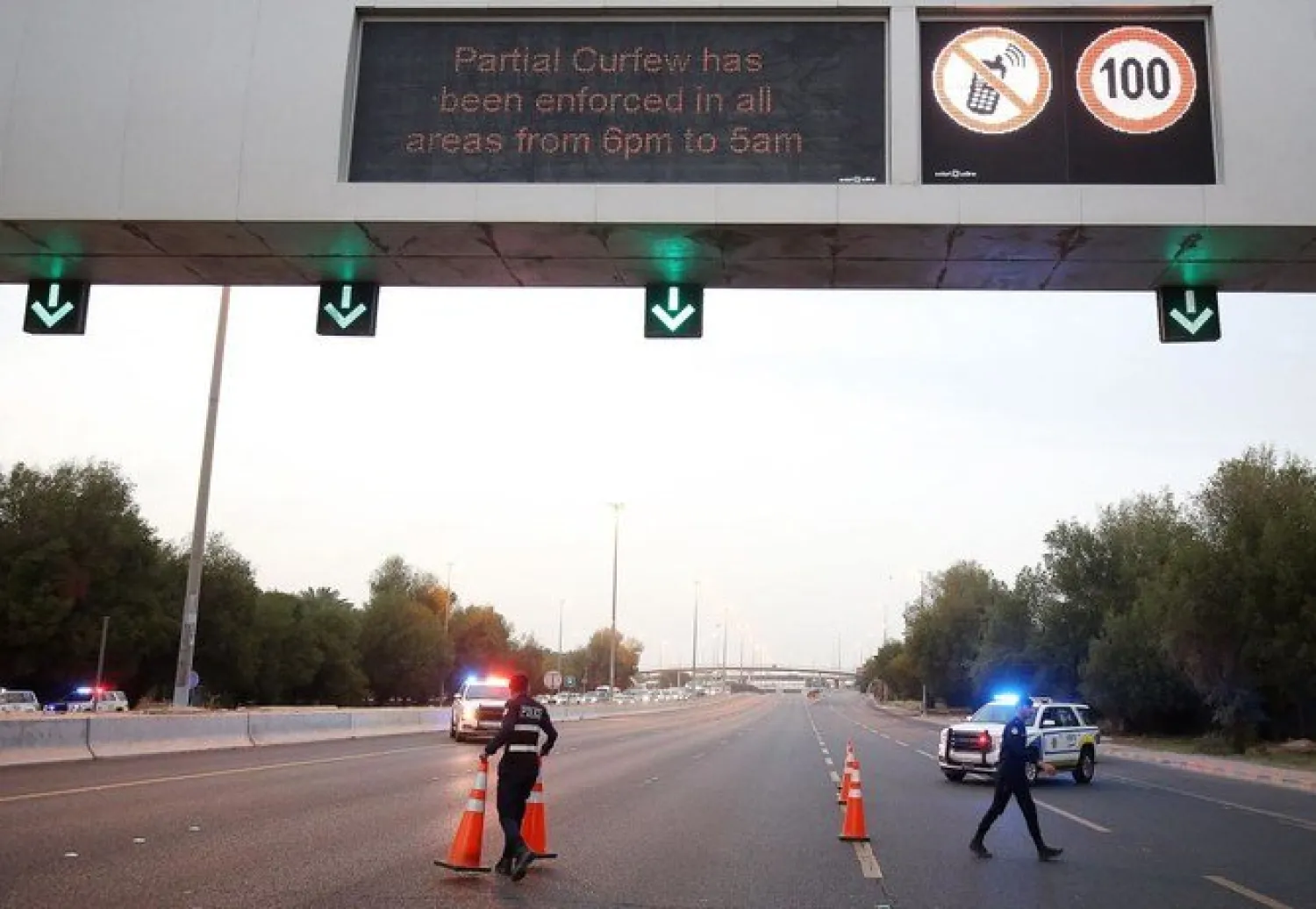 Kuwaiti policemen set up a check point on King Faisal road to control drivers during a curfew imposed by the authorities in a bid to stem the spread of the coronavirus, in Kuwait City, on April 1, 2021. (AFP)
