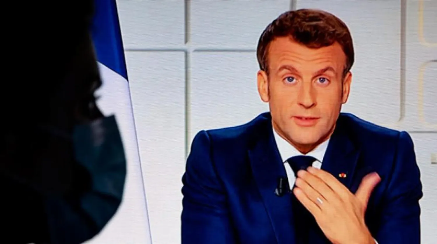 Macron’un çarşamba günkü konuşmasını dinleyen bir kadın (EPA)