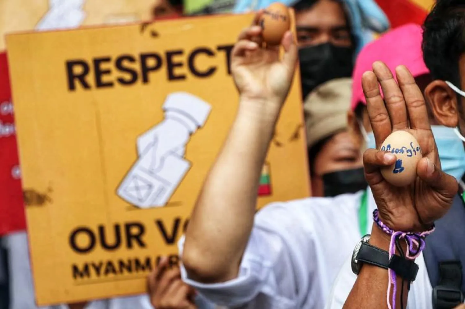 محتجون يرفعون صورا لبيض كُتب عليه شعارات مناهضة للنظام في ميانمار (أ.ف.ب)
