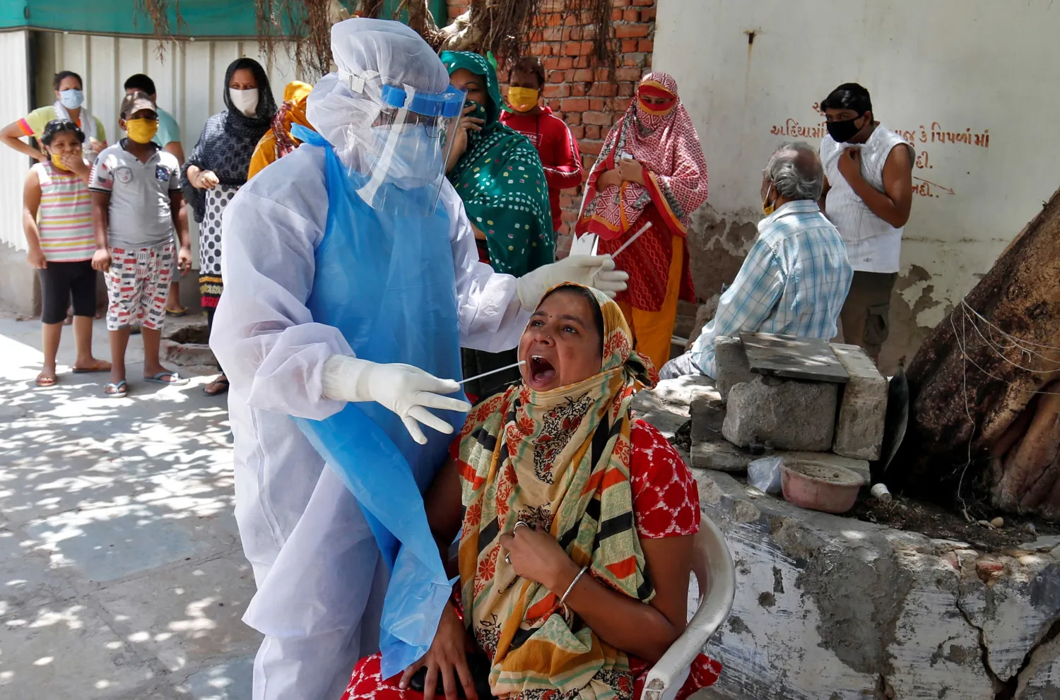 A woman reacts as a healthcare worker wearing a protective gear takes a swab to test for the coronavirus disease (COVID-19) at a residential area in Ahmedabad, India. Reuters file photo