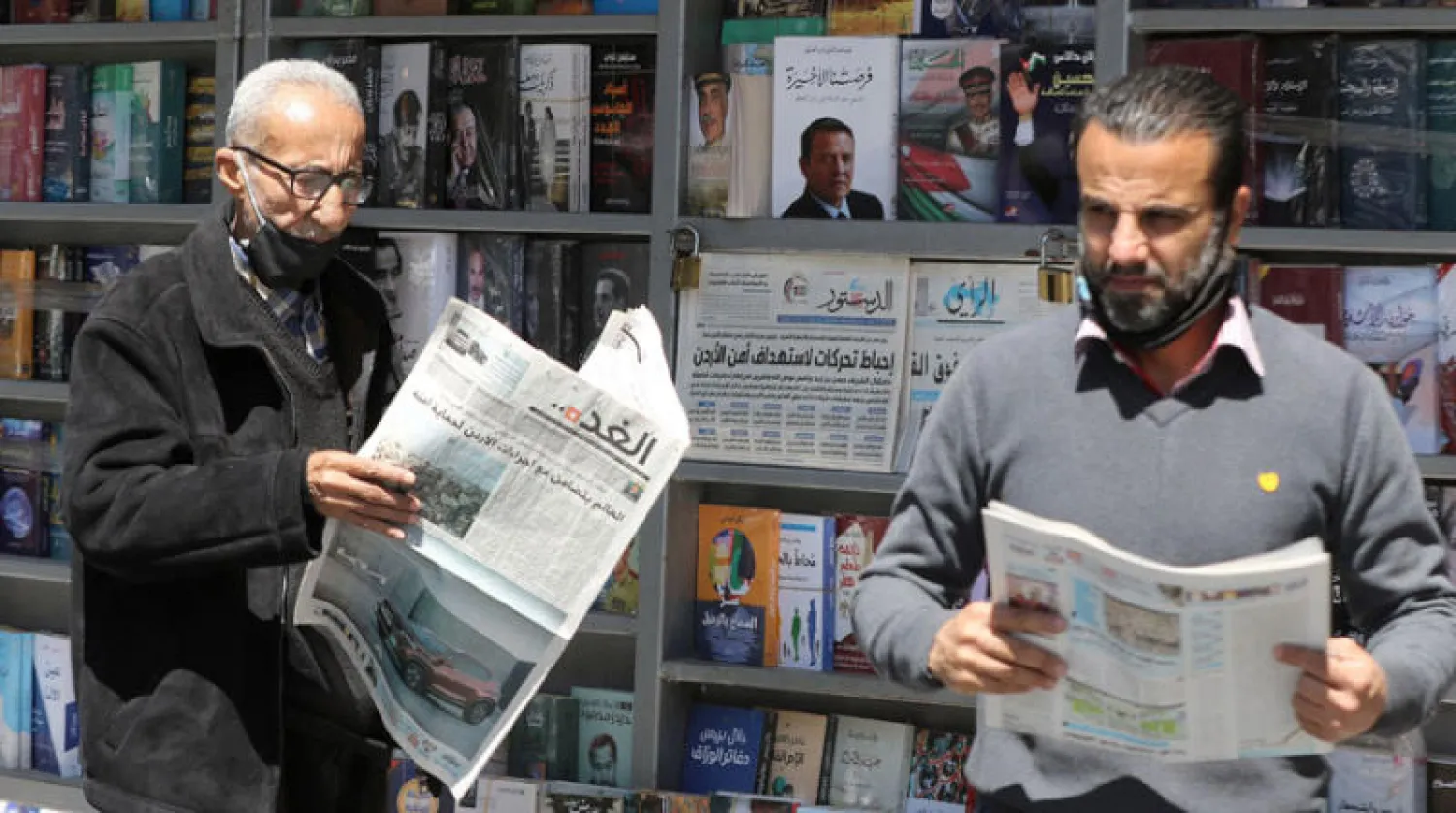 مواطنان أردنيان يتابعان أحداث الأردن عبر مانشيتات الصحف المحلية (أ.ف.ب)