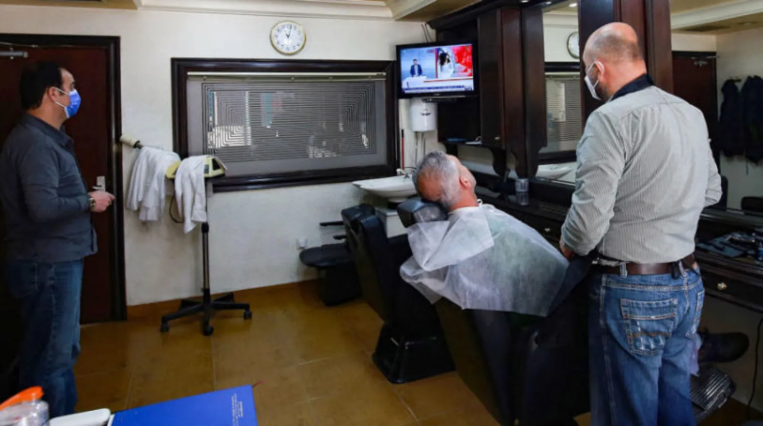 متابعة المؤتمر الصحفي لنائب رئيس الوزراء الأردني أيمن الصفدي داخل صالون للحلاقة في عمان امس (إ ف ب)