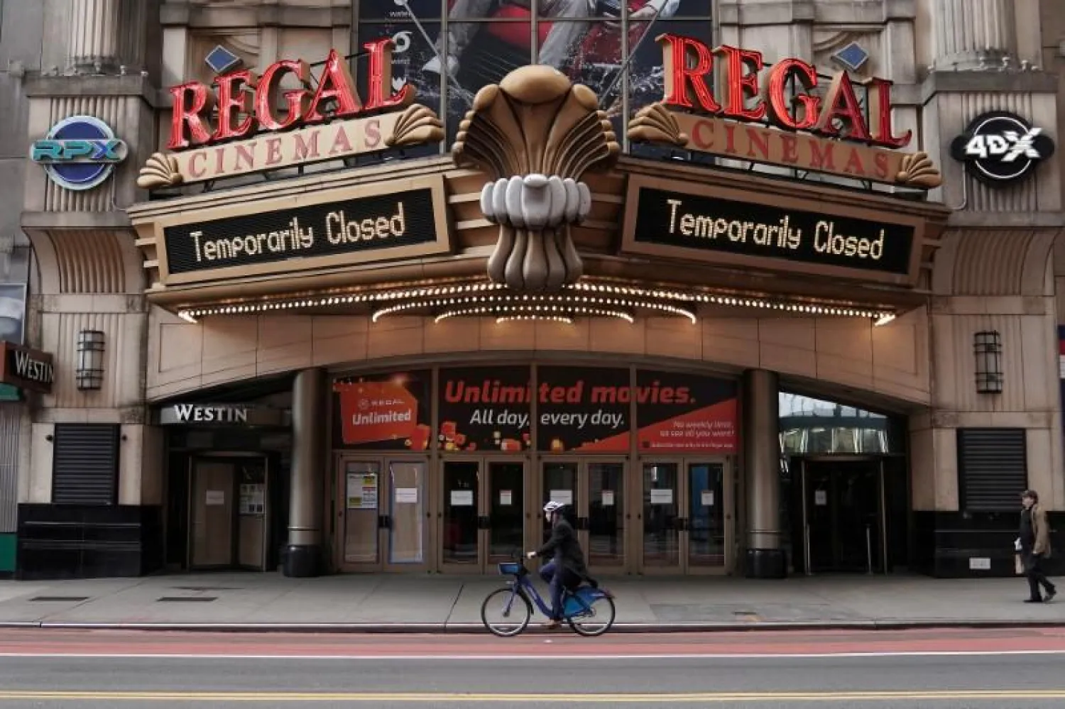 FILE PHOTO: A man cycles past a shuttered movie theater in Times Square following the outbreak of coronavirus disease (COVID-19), in the Manhattan borough of New York City, New York, US, March 17, 2020. REUTERS/Carlo Allegri
