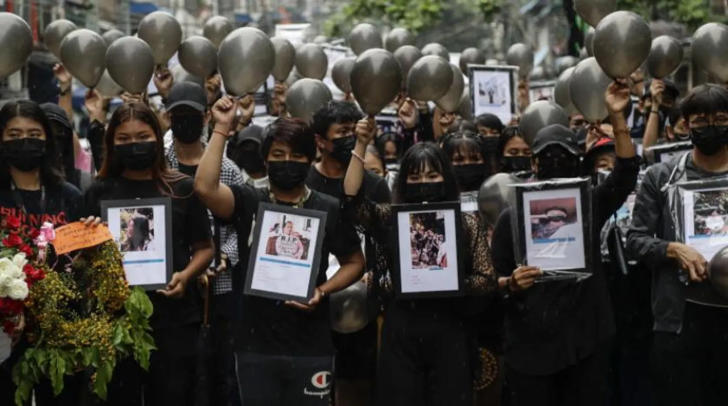 Darbe karşıtı protestocular, Yangon’daki protestolar sırasında güvenlik güçleri tarafından öldürülen kurbanların fotoğraflarını taşıyor (EPA)