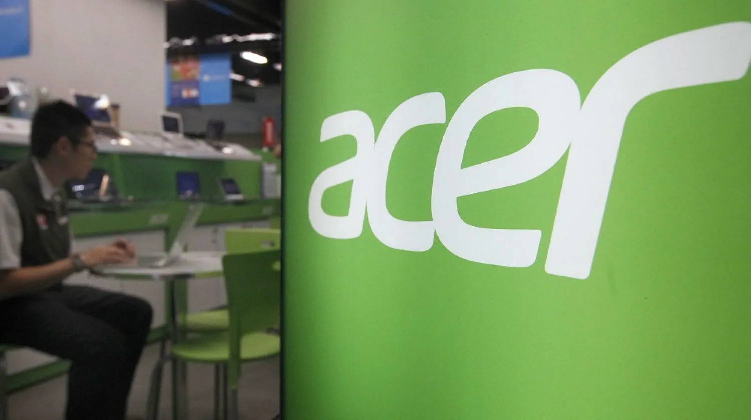 A shop attendant sits in an Acer booth in a computer mall in Taipei March 19, 2013. (Reuters)