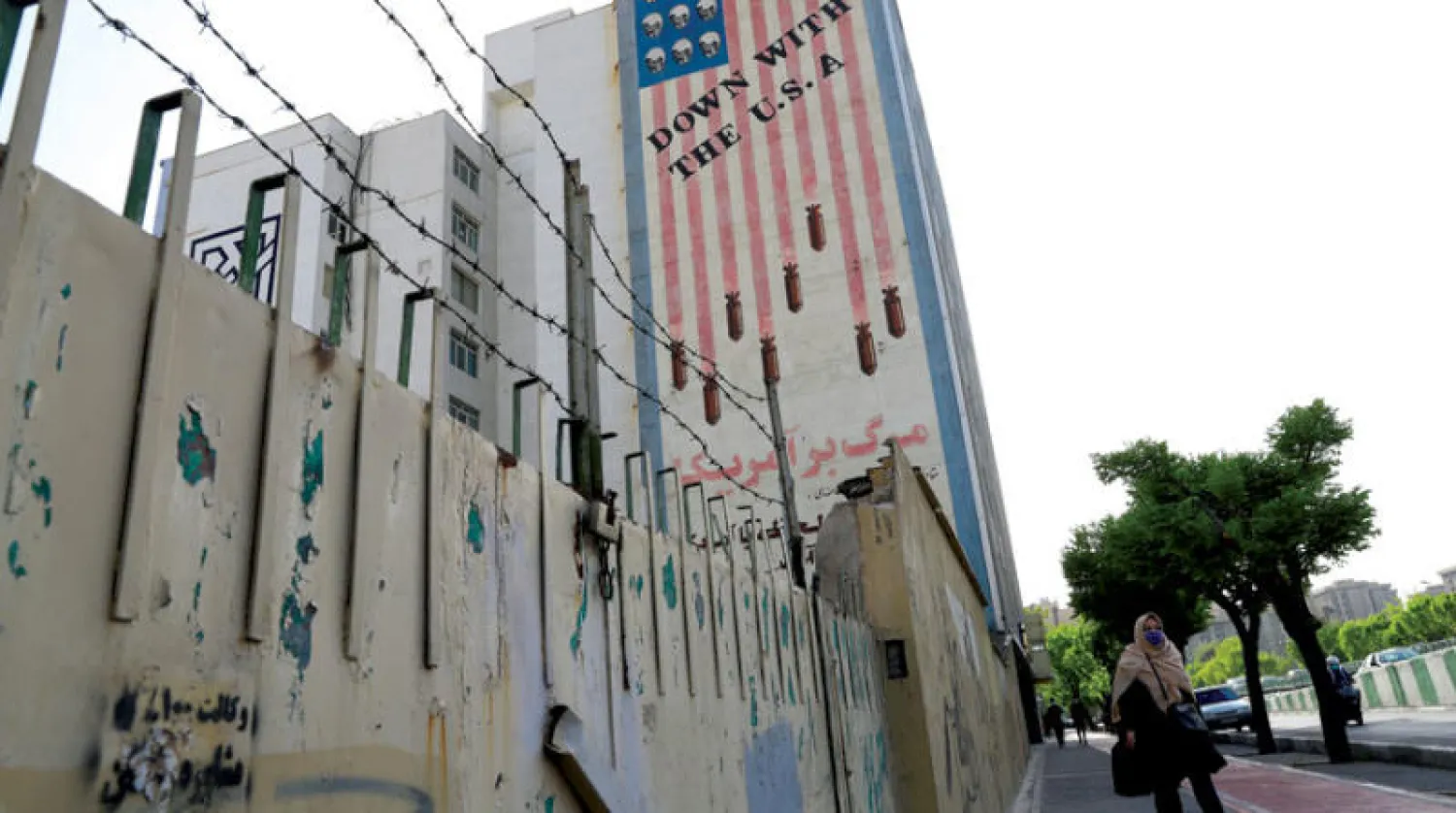 امرأة إيرانية تمشي في شارع تبدو جدارية معادية لأميركا علی ‌أحد مبانیه في طهران ‌أمس (رويترز)