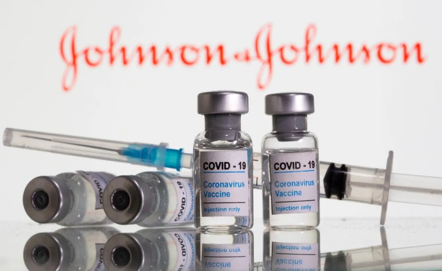 Vials labeled "COVID-19 Coronavirus Vaccine" and sryinge are seen in front of displayed J&J logo in this illustration | REUTERS