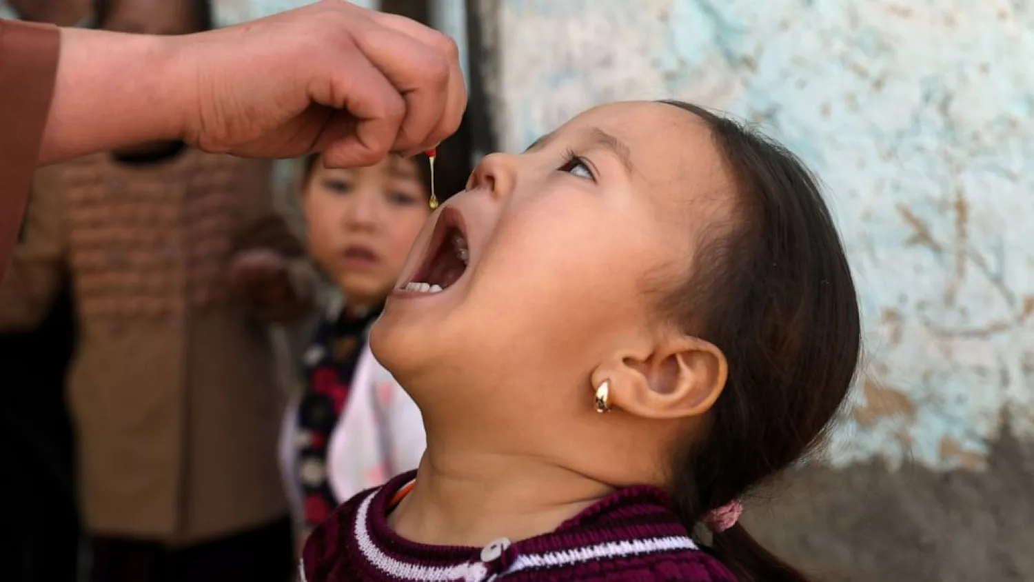 Shabana Maani, gives a polio vaccination to a child in the old part of Kabul, Afghanistan, Monday, March 29, 2021. Afghanistan is inoculating millions of children against polio after pandemic lockdowns stalled the effort to eradicate the crippling disease. But the recent killing of three vaccinators points to the dangers facing the campaign. (AP Photo/Rahmat Gul)