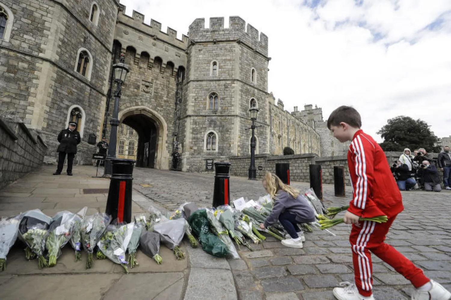 طفلان يضعان الأزهار خارج قلعة ويندسور بعد وفاة الأمير فيليب اليوم (أ.ب)