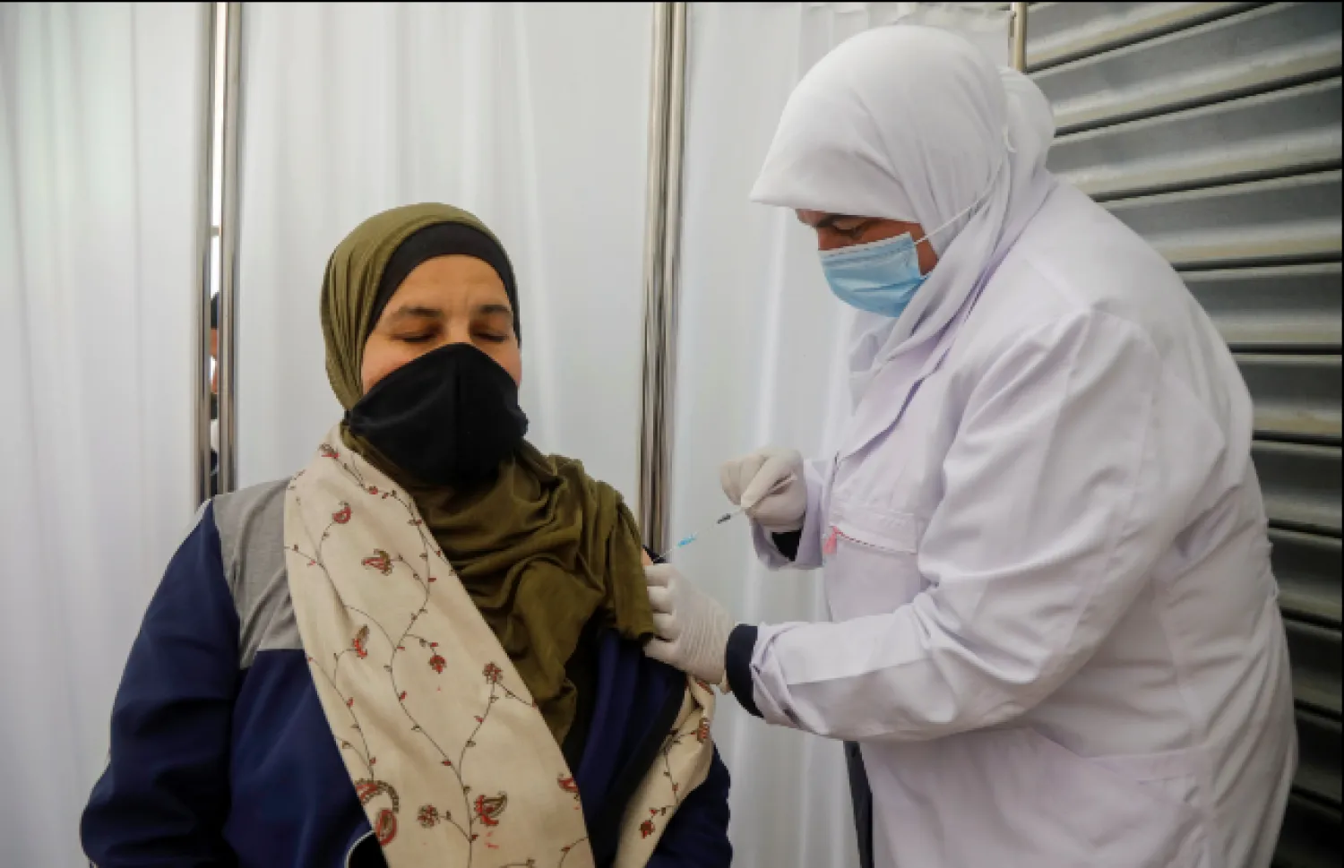  A Palestinian member of the education staff receives coronavirus vaccine as schools are set to reopen partially, in Tubas in the Israeli-occupied West Bank, April 6, 2021. (REUTERS)

