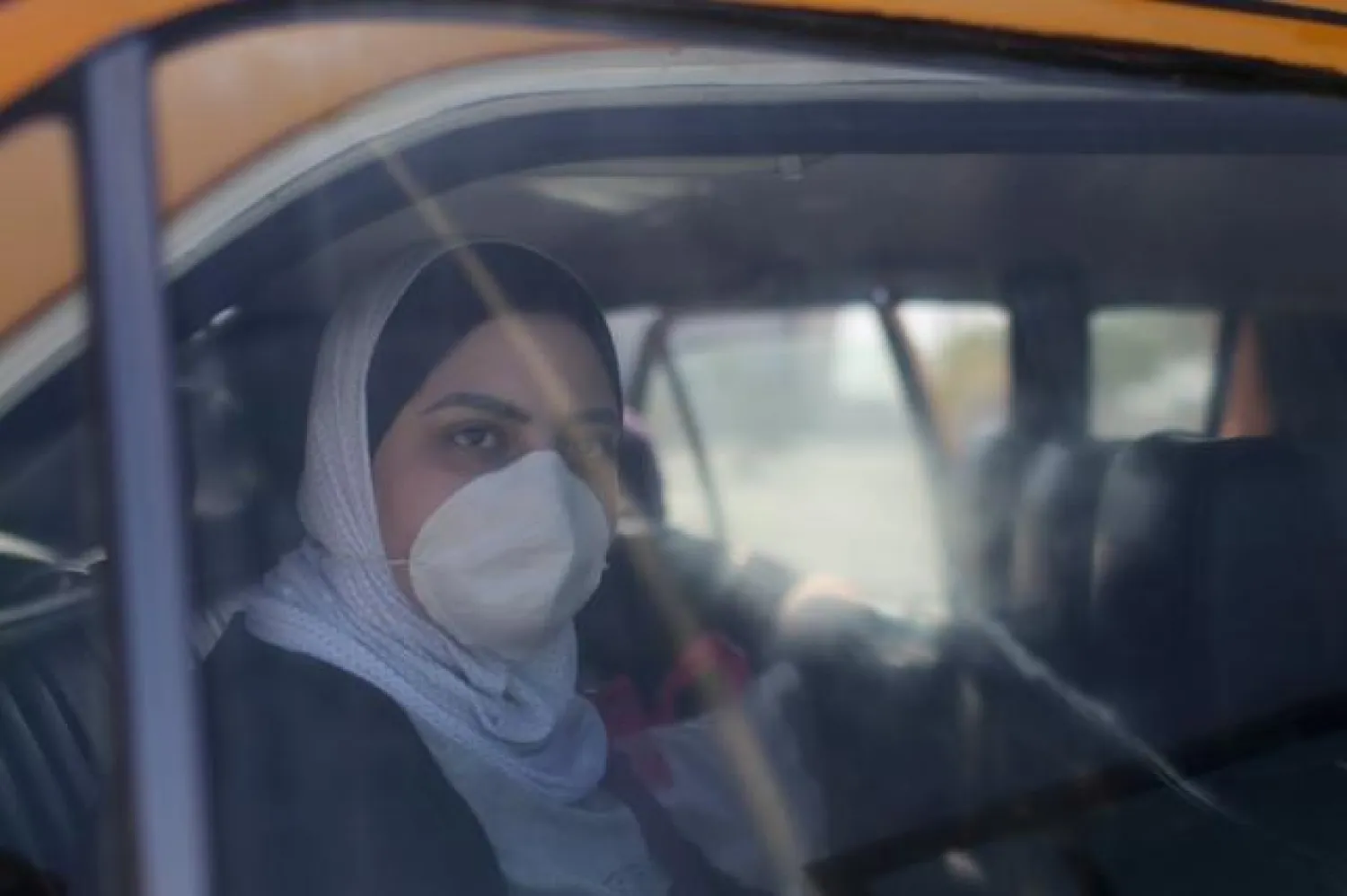 FILE PHOTO: A Palestinian woman, wearing a mask as a preventive measure against coronavirus, looks out of a car upon her return from abroad, at Rafah border crossing in the southern Gaza Strip March 8, 2020. REUTERS/Ibraheem Abu Mustafa/File Photo
