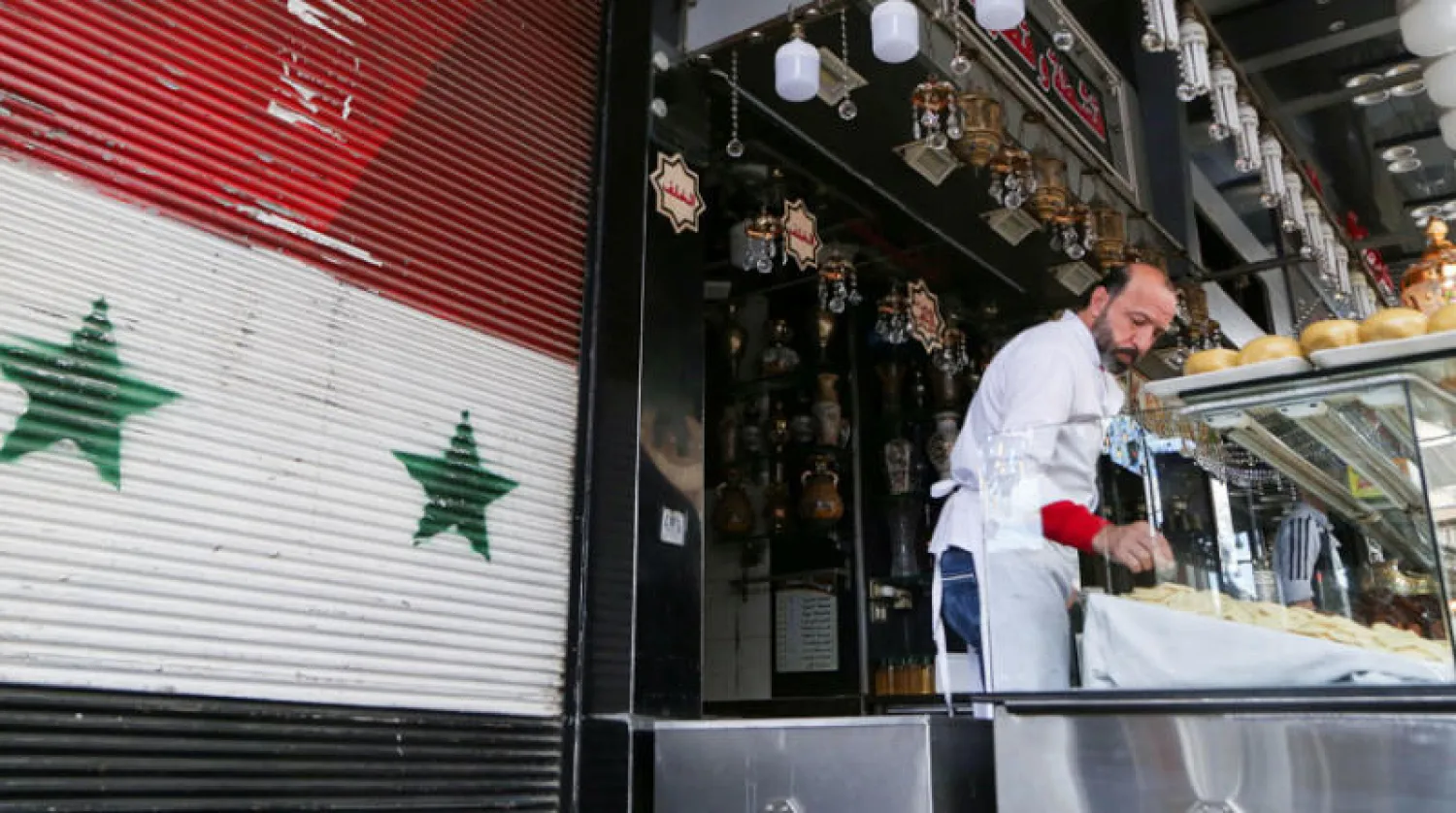 بائع حلويات قرب العلم السوري في دمشق أول من أمس (رويترز)