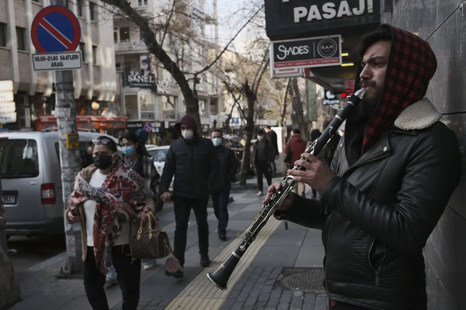 People wearing masks to help protect against the spread of coronavirus, walk past a musician in Ankara, Turkey, April 2, 2021. (AP)