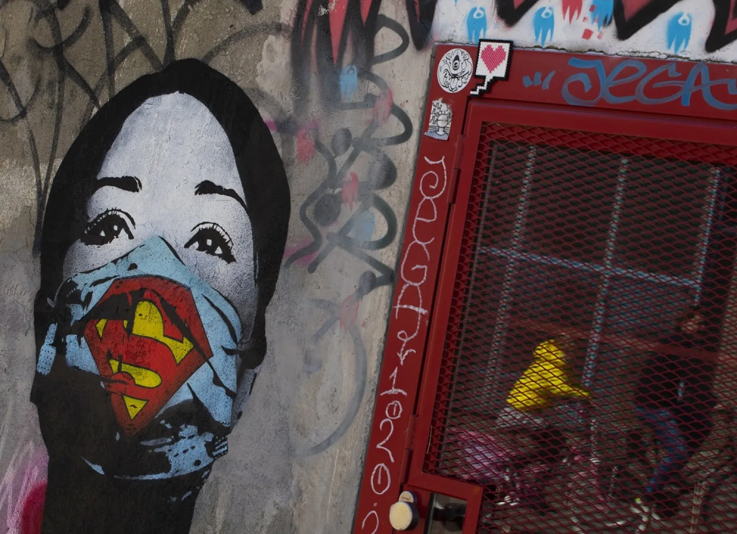 A mother and her child are reflected as they pass a mural by artist FAKE, titled "Super Nurse", paying tribute to all healthcare and medical professionals in times of the coronavirus, in Amsterdam, Netherlands, Sunday, April 19, 2020. (AP)