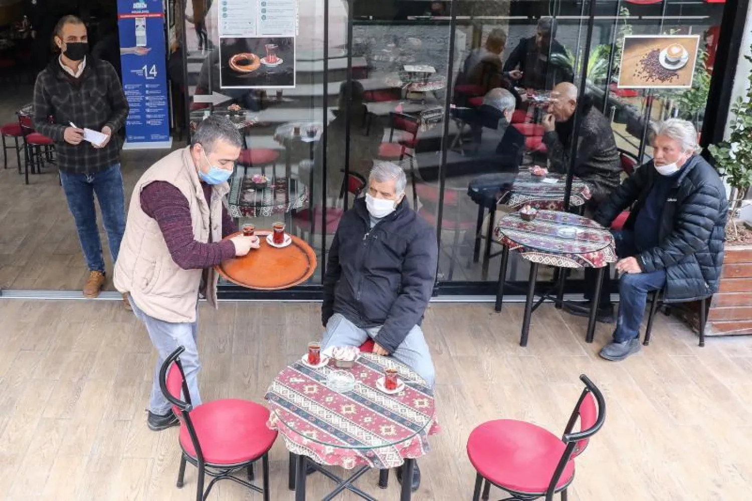 أشخاص يضعون الكمامات في مطعم بأنقرة (أ.ف.ب)