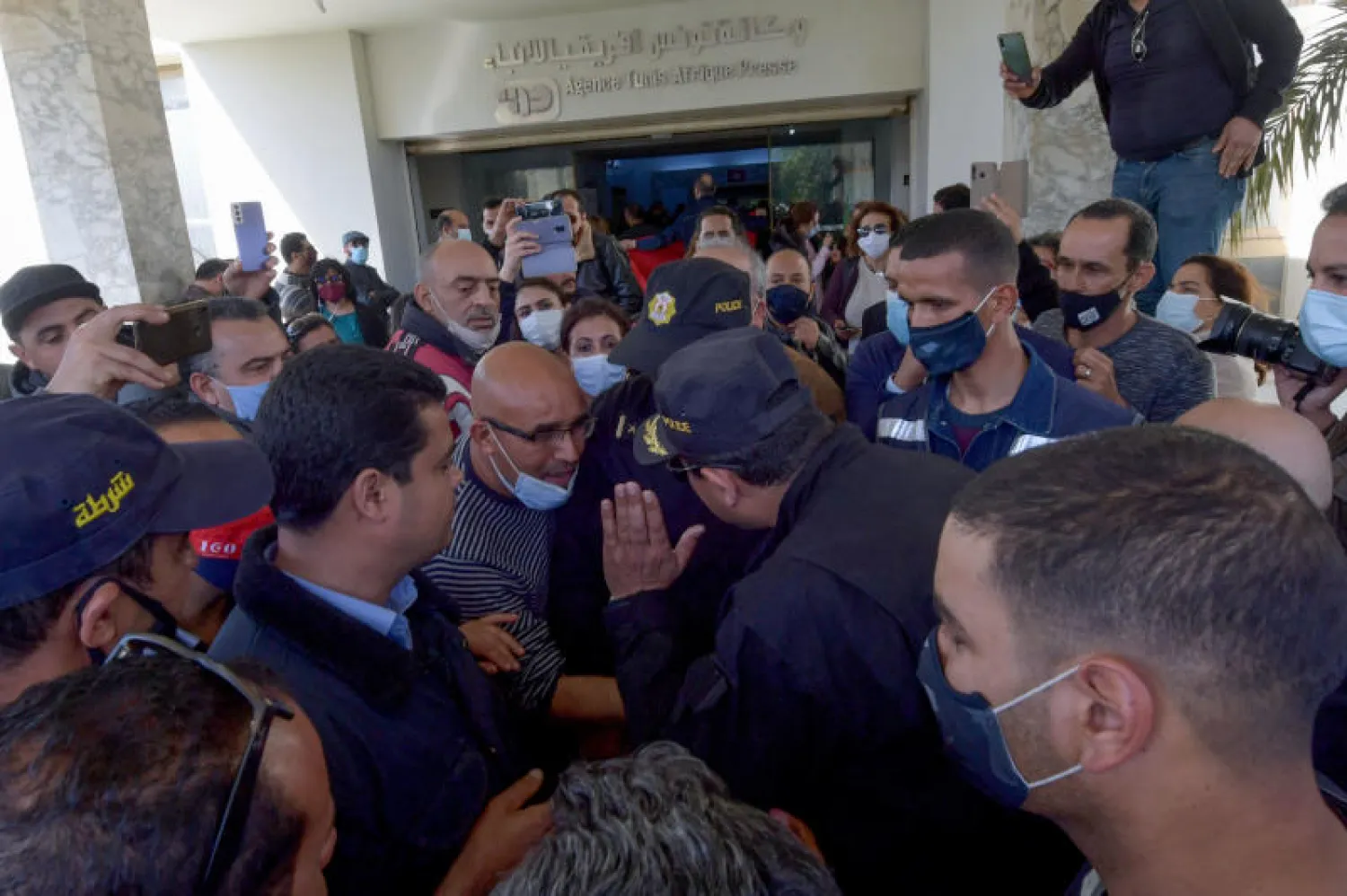 رجال شرطة يتجادلون مع الصحافيين أمام مقر وكالة الأنباء التونسية (أ.ف.ب)