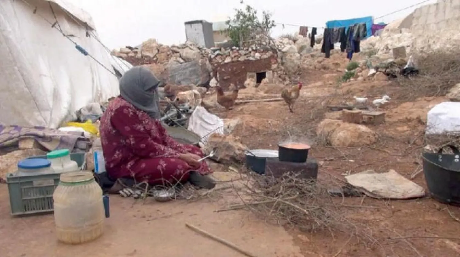 Yerinden edilmiş bir kadın kuzeybatı Suriye'deki çadırının yanında yemek pişiriyor (Şarku’l Avsat)