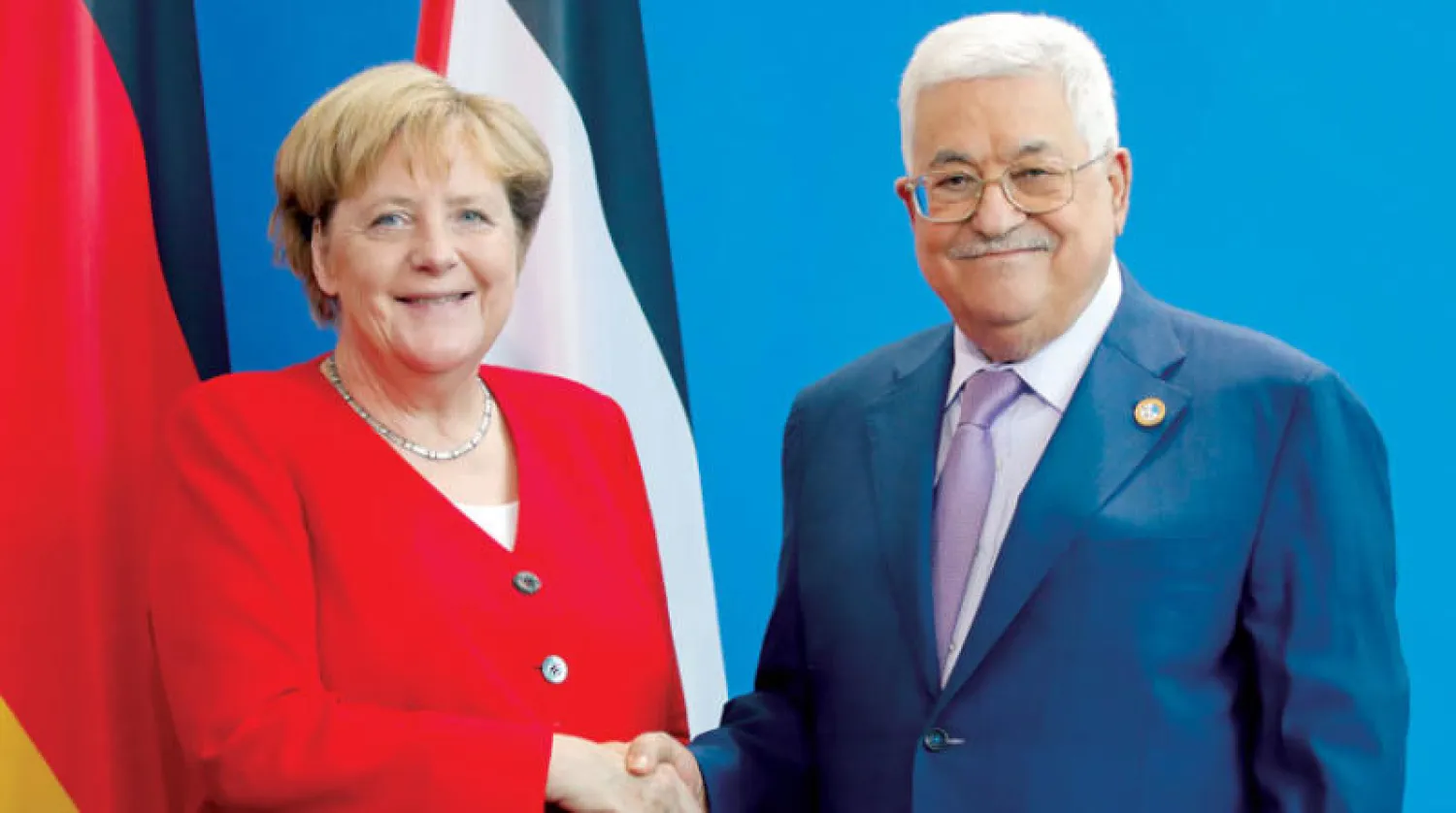 عباس مصافحاً ميركل لدى زيارته برلين في 2019 (رويترز)