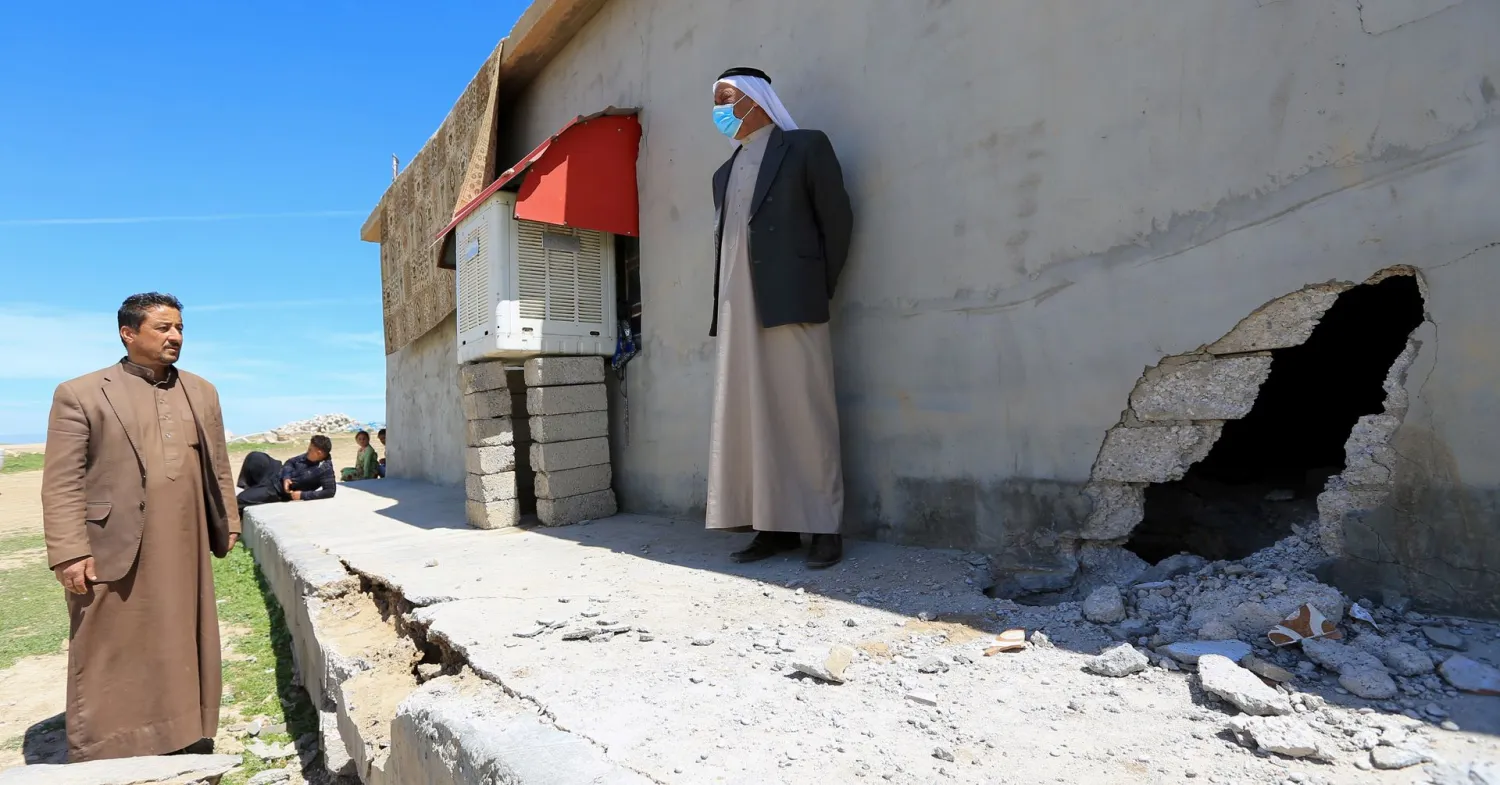 People stand next to a damaged house after a rocket attack on a military compound, at a village in Bashiqa region, Iraq, April 15, 2021. REUTERS/Ari Jalal