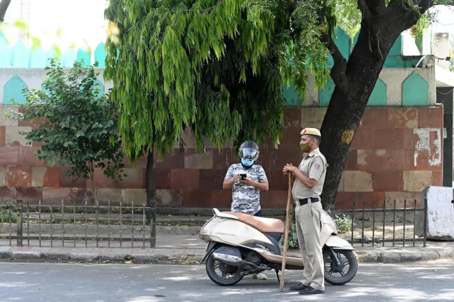 شرطي يدقق في أوراق دراج في نيودلهي الخاضعة لتدابير إغلاق (أ.ف.ب)