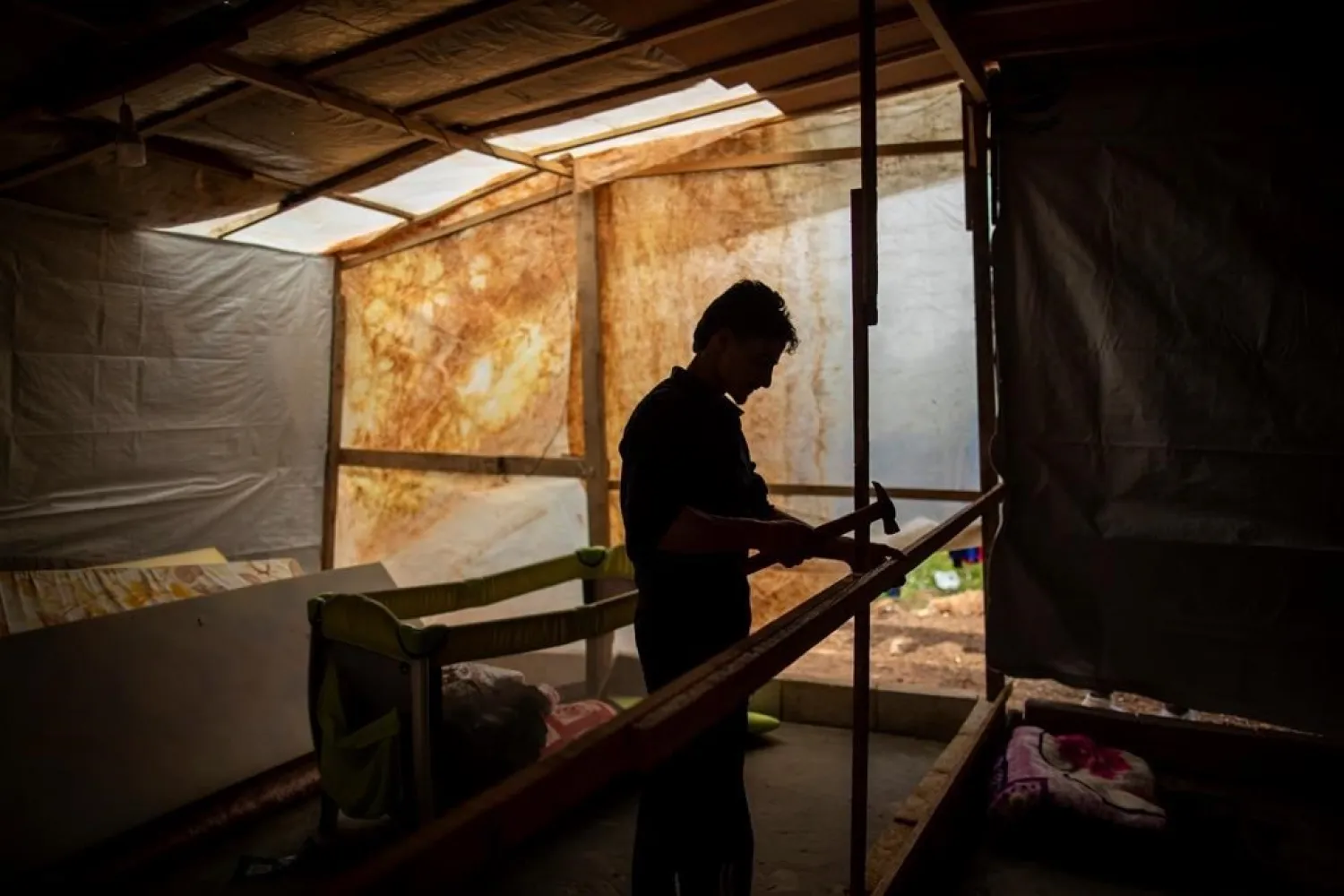 Syrian refugee Raed Mattar, 24, works on his tent, at an informal refugee camp, in the town of Rihaniyye in the northern city of Tripoli, Lebanon, Thursday, April 8, 2021. (AP)
