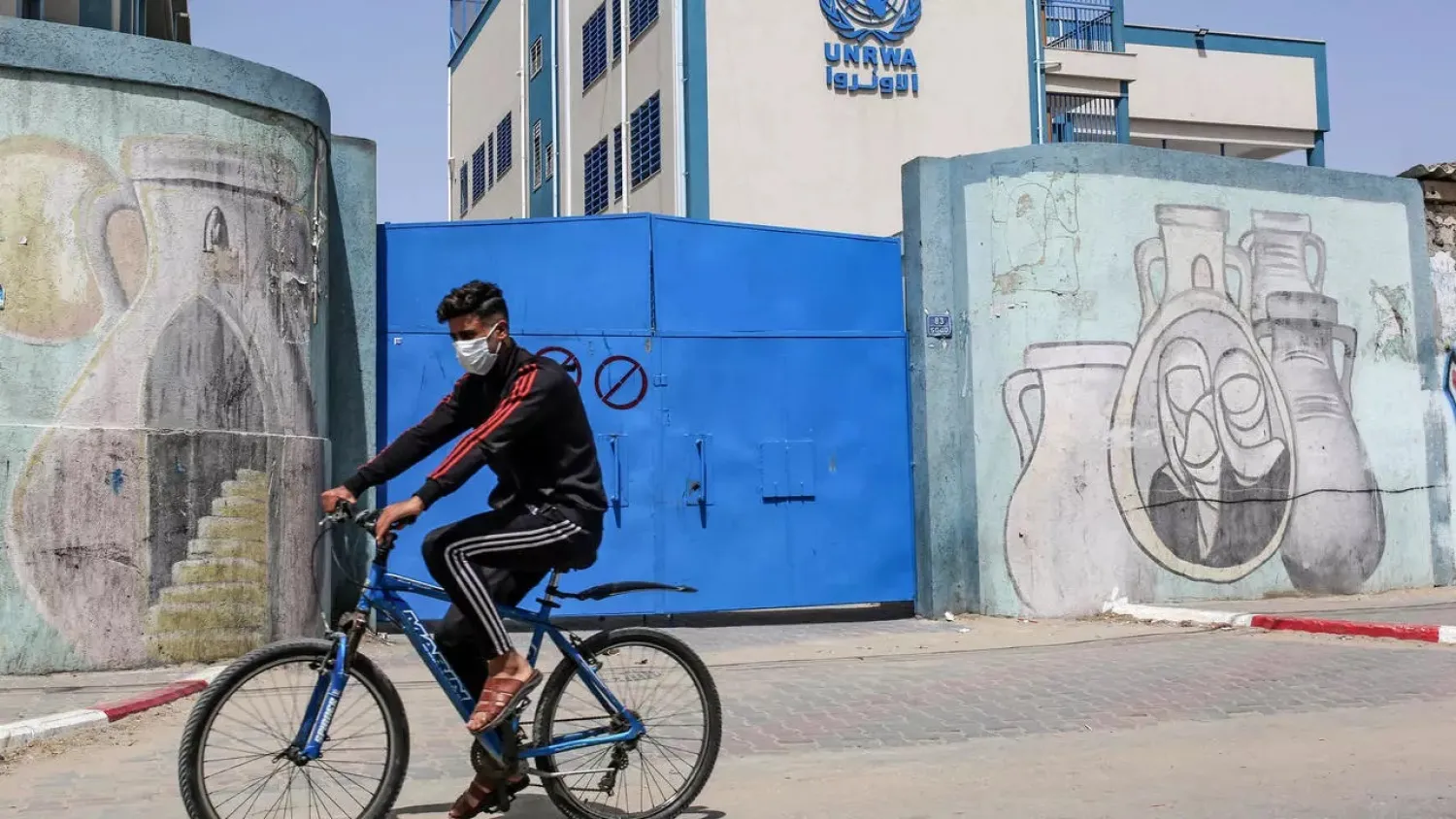 A Palestinian rides a bicycle past the closed gate of a school run by the United Nations Relief and Works Agency for Palestinian Refugees (UNRWA) in the city of Rafah in the Gaza Strip. (AFP)