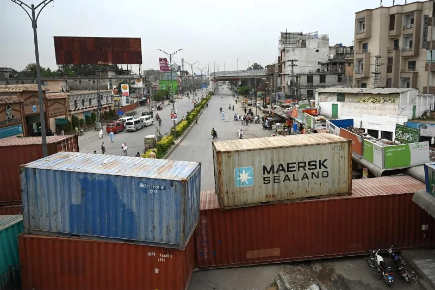 مشاة عند نقطة الدخول الرئيسية بين روالبندي وإسلام آباد التي تم حظرها بواسطة حاويات الشحن بسبب الاحتجاجات (أ.ف.ب)