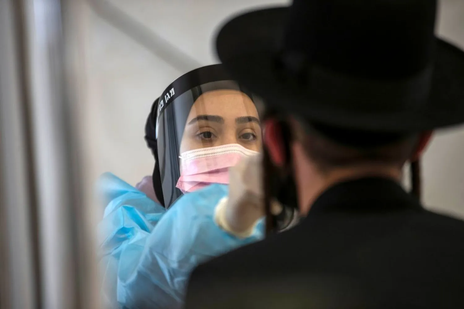 A healthcare worker takes a swab sample from an Ultra-Orthodox Jewish man for the COVID-19 test, at Ben Gurion International Airport in Lod, near Tel Aviv, Israel April 13, 2021. (Reuters)