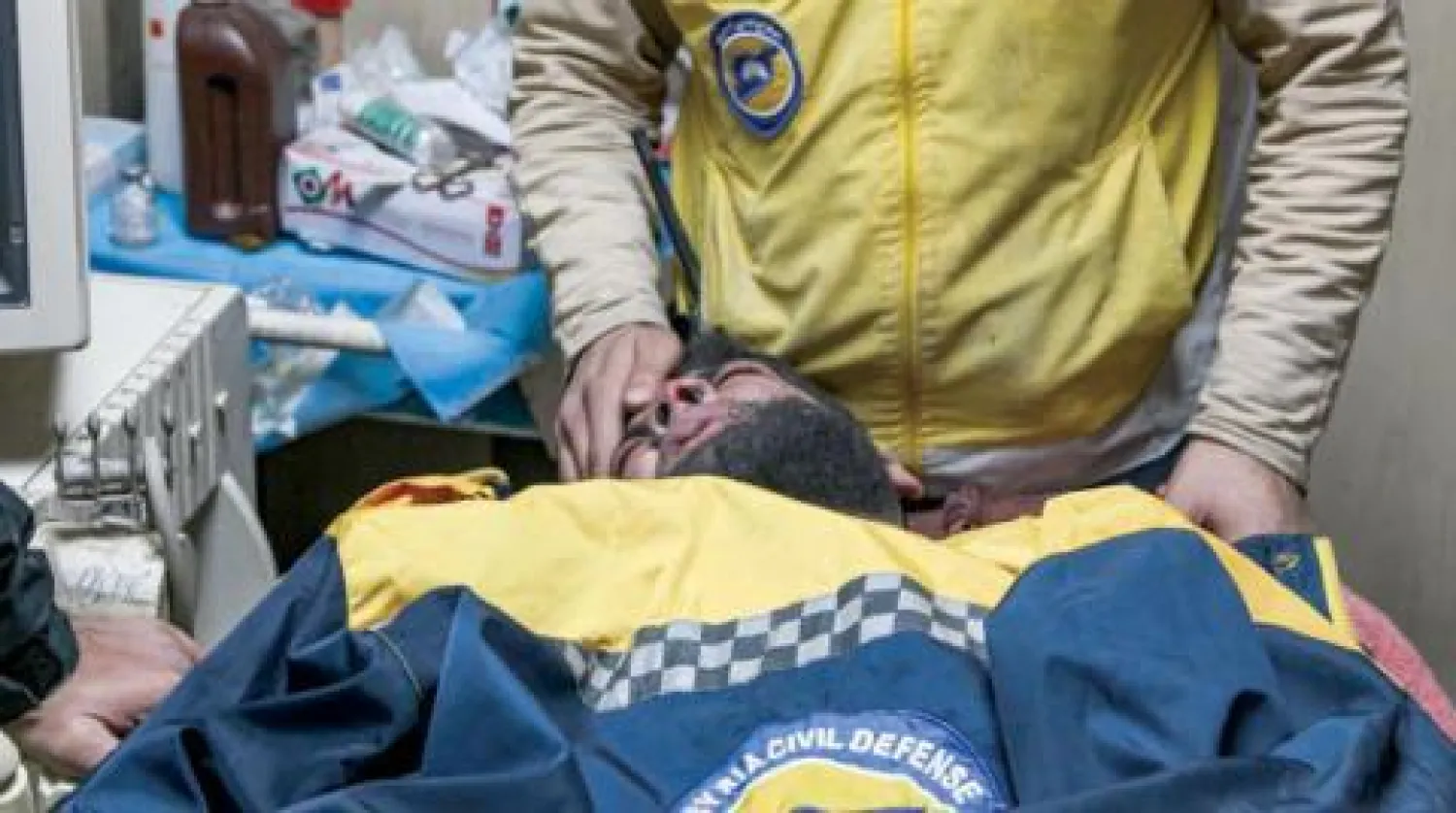 عنصر من الدفاع المدني يهدئ زميله المصاب بعد غارة على سراقب العام الماضي (غيتي)