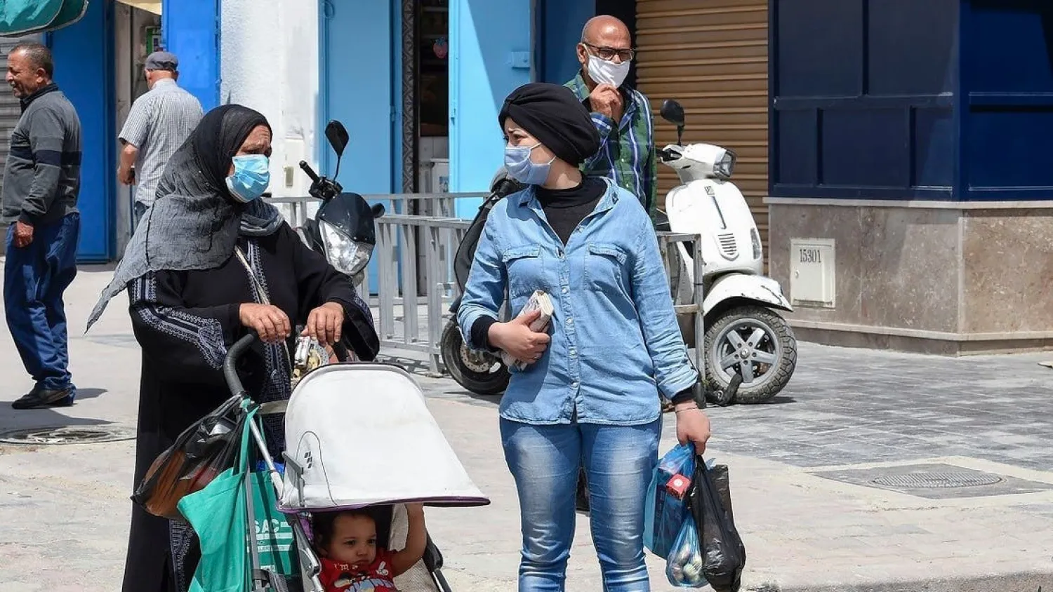 Tunisians wearing protective masks walk in a street in the capital Tunis. (AFP)
