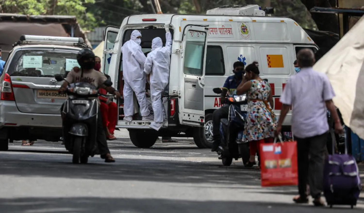 عاملون صحيون ينقلون مريضاً مشتبه بإصابته بفيروس كورونا في مومباي بالهند (إ.ب.أ)