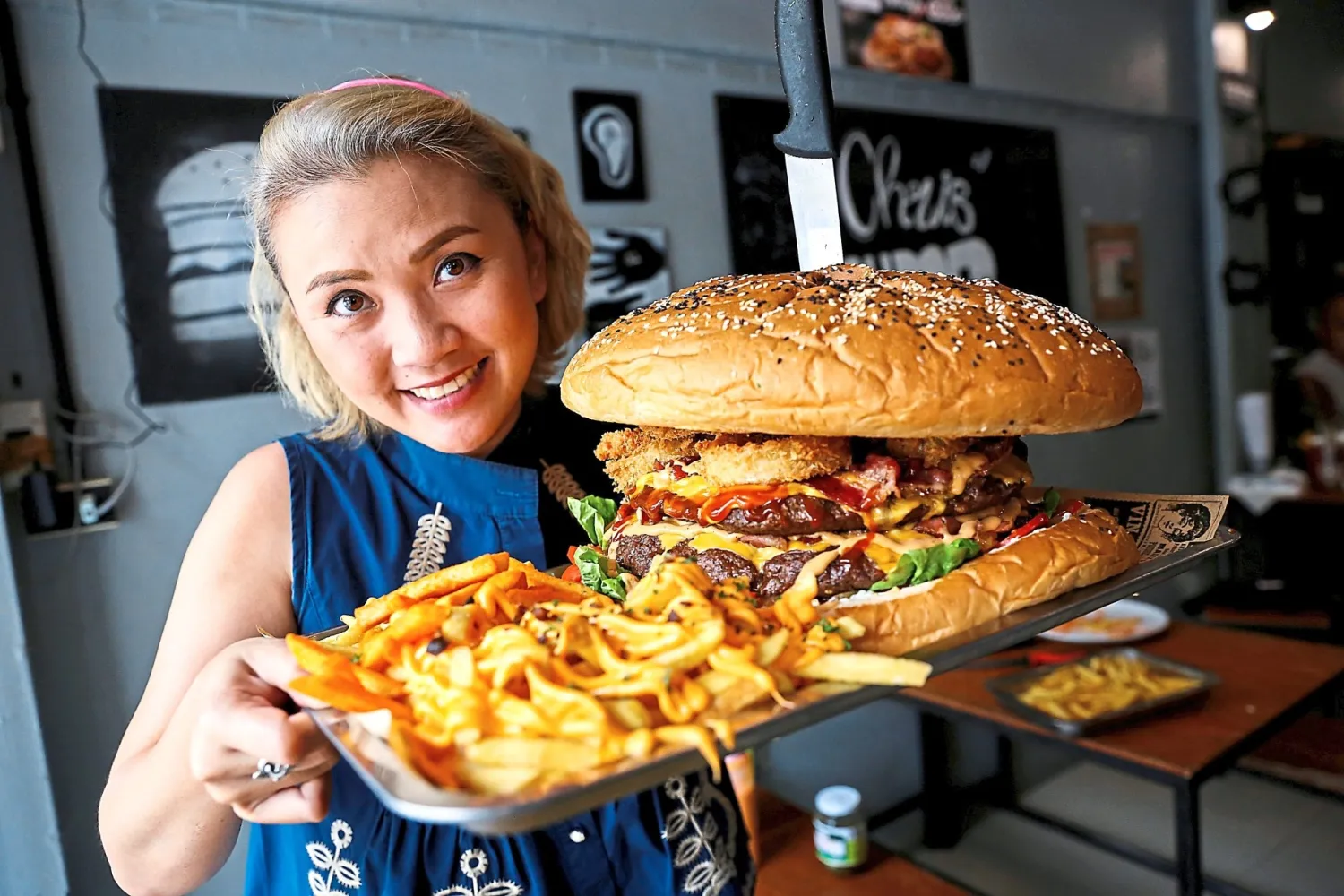 A woman holding up the “6kg Burger” at Chris Steaks and Burgers
in Bangkok. — Reuters
