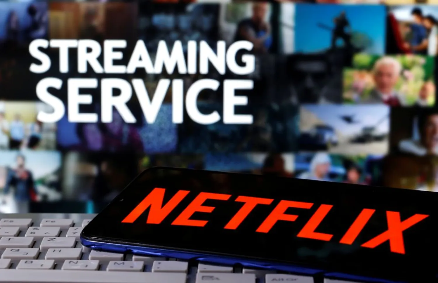 A smartphone with the Netflix logo is seen on a keyboard in front of displayed "Streaming service" words in this illustration taken March 24, 2020. REUTERS/Dado Ruvic