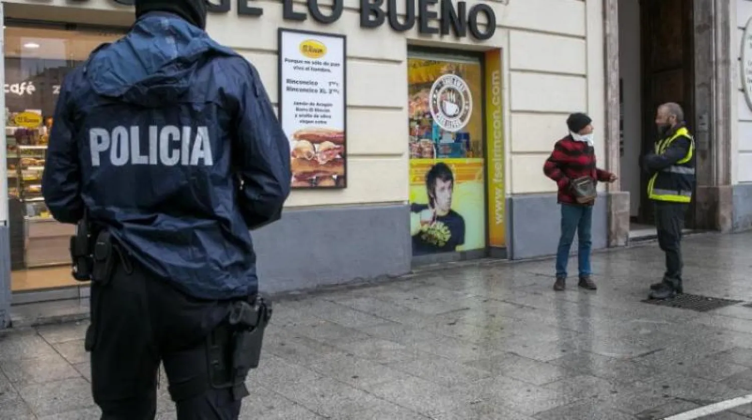 شرطي في مدينة سرقسطة (شمال شرق) الإسبانية يسأل رجلاً عن سبب وجوده في الشارع (إ.ب.أ)