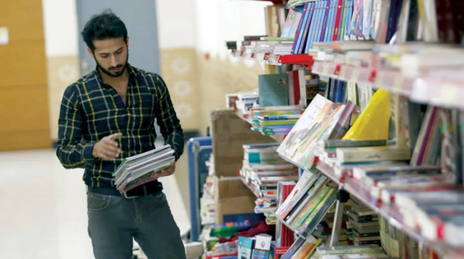 شاب عراقي يقف في مكتبته بالبصرة (أ.ف.ب)